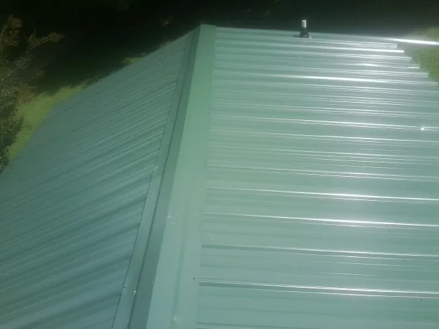 New green metal panels meeting at the ridge of a roof — Flat Roof Repair work by our crew in Freeport